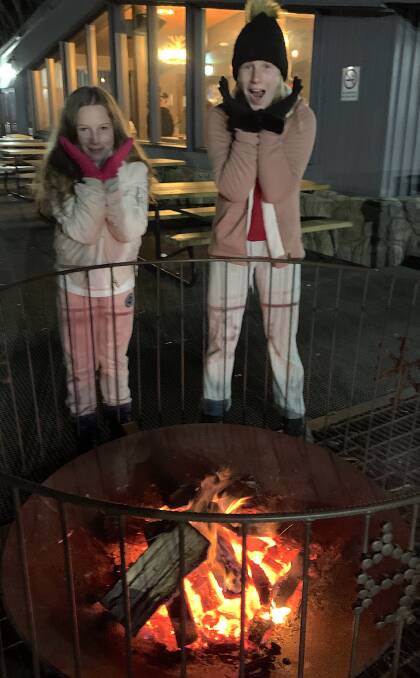 Tims daughters Emily and Sarah warm-up by the fire pit at Merritts Mountain Haus. Picture: Tim the Yowie Man