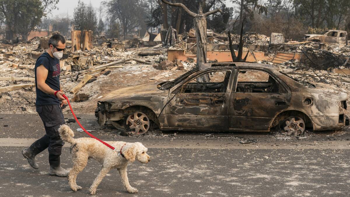 Jerod Knox walks his dog, Bear, through his neighbourhood in Talent, Oregon, where hundreds of homes, including his own, were destroyed. Picture: Getty Images