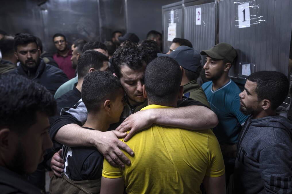 Mourners comfort each other in the morgue of Al-Shifa Hospital after Israeli airstrikes killed a dozen Palestinians. Picture AAP