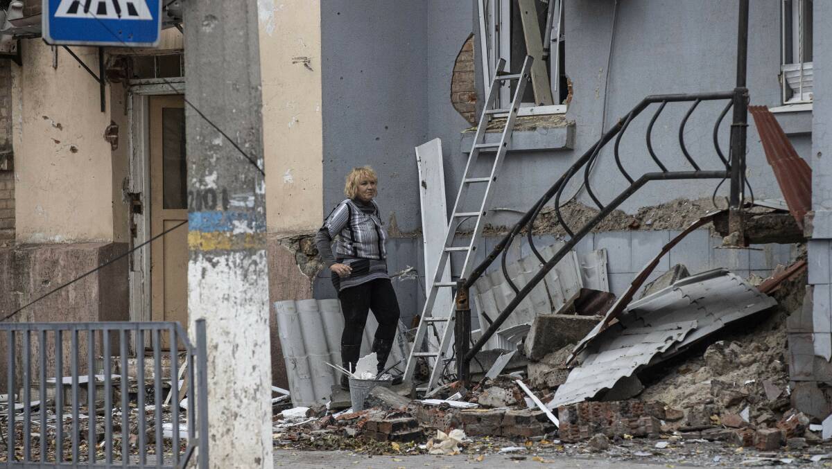 A Ukrainian civilian gets into her house from its window with a ladder in Bakhmut city. Treasurer Jim Chalmers can blame the war in Ukraine as a reason why electricity and gas prices remain high. Picture Getty Images