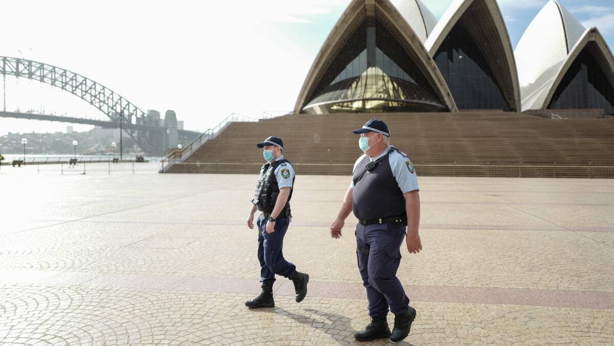 NSW police officers patrol the Opera House on Sunday after new lockdown restrictions were tightened. Picture: Getty Images