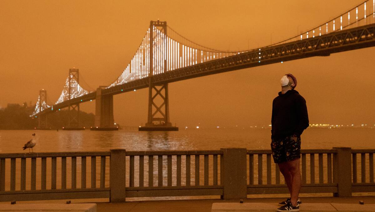 Eli Harik of San Francisco wears a mask while looking up at the orange sky over the Golden Gate Bridge. Picture: Getty Images