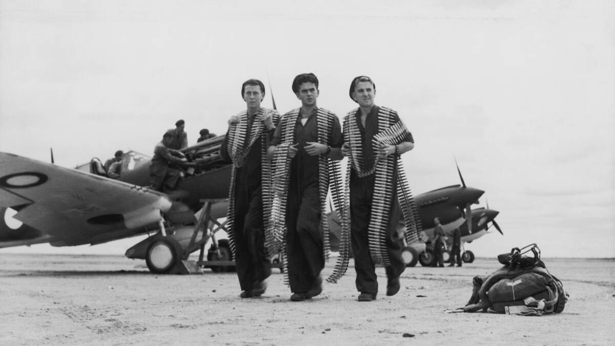 Royal Australian Air Force mechanics carrying ammunition belts for Curtiss P-40 Kittyhawk fighters at an Australian airfield, circa 1943. Picture: Getty Images