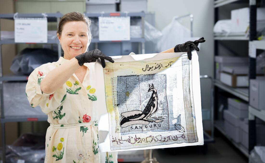 Australian War Memorial curator Lara Nicholls holds a hankerchief with the message "My wish is for peace in my country". Picture by Sitthixay Ditthavong