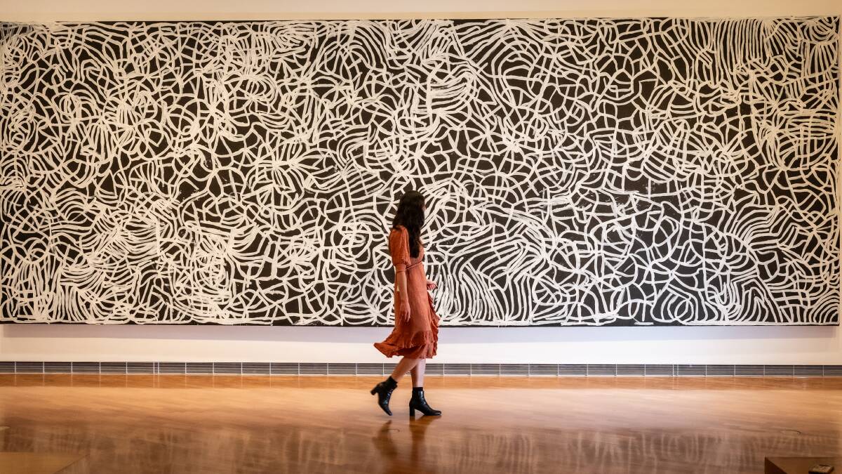 A gallery-goer contemplates Emily Kam Kngwarray's eight-metre Anwerlarr Anganenty (Big Yam Dreaming). Picture by Karleen Minney