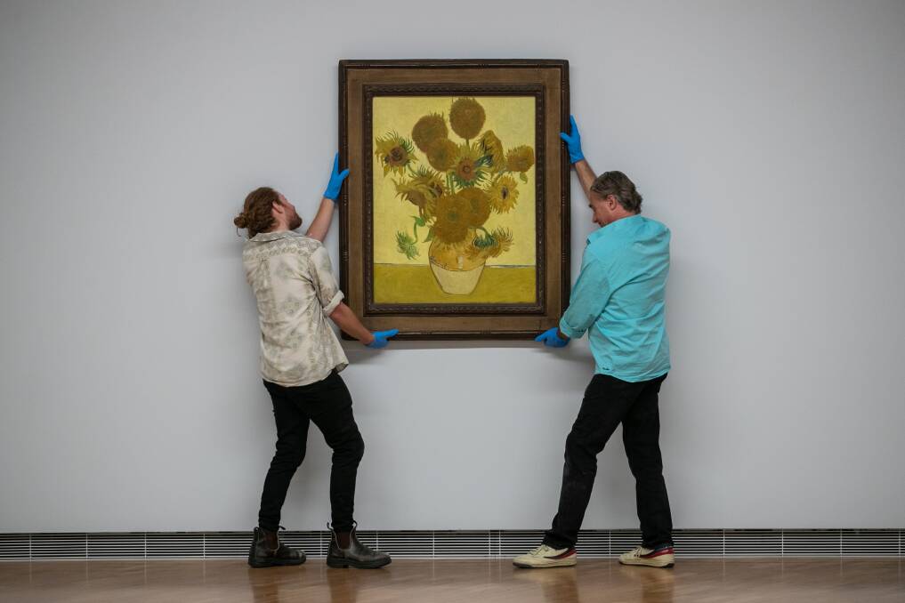 Joel Arthur and Lloyd Hurrell hanging Vincent Van Gogh's Sunflowers at the National Gallery of Australia. Picture: Keegan Carroll