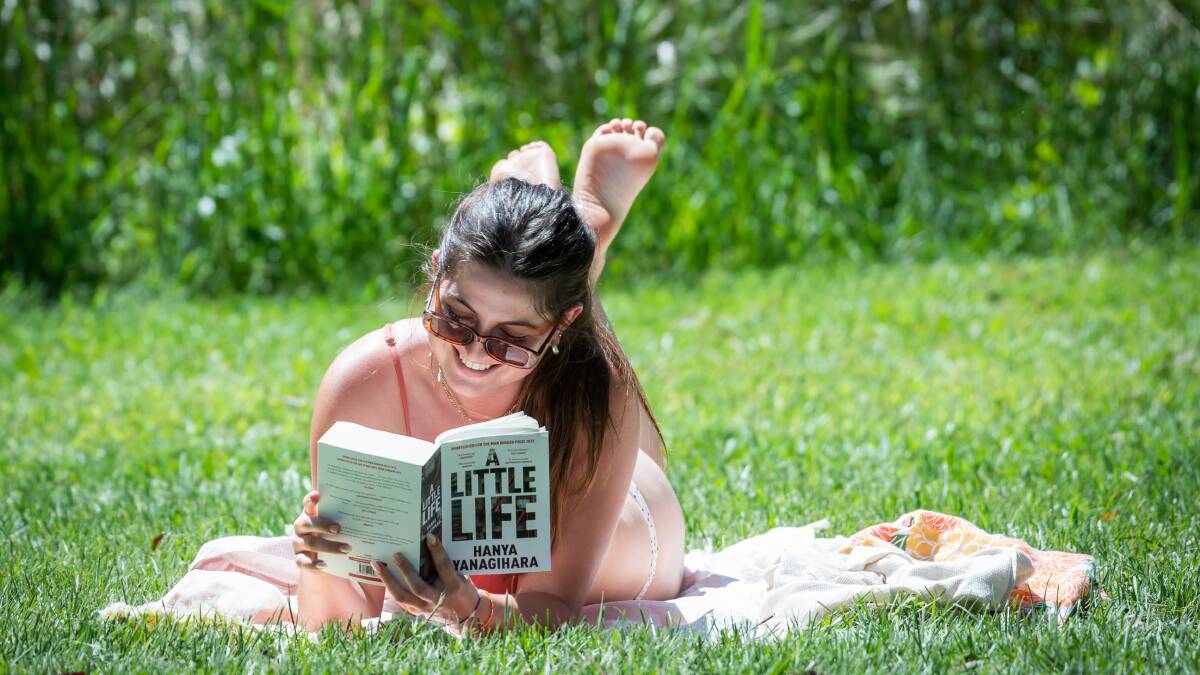 Bikini clad Emily Bannister reads a book in the sunshine on the grounds of the ANU. Picture by Karleen Minney