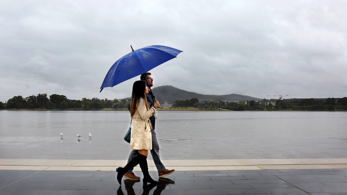 Residents brave the rain and walk along the lake. Picture by James Croucher