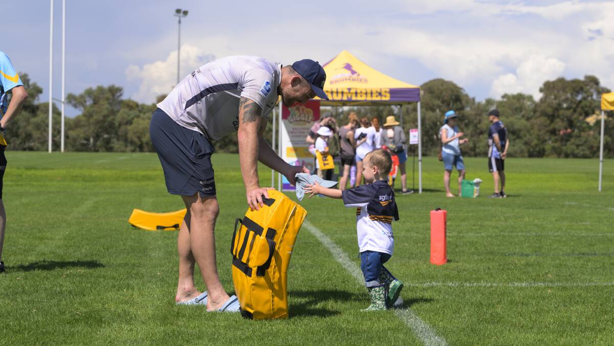Cadeyrn Neville plays with his son Lewis at Sunday's fan day. The ACT Brumbies lock is hoping to return from a hamstring injury against the Rebels on Friday. Picture by Keegan Carroll