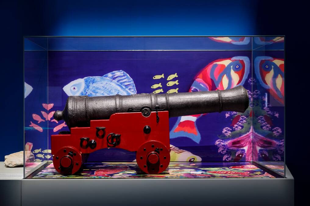 A cannon jettisoned from the Endeavour in 1770 against the backdrop of Gertie Deerals 2019 artwork Reef, Hopevale Arts and Culture Centre. Photos supplied. National Museum of Australia (Jason McCarthy)