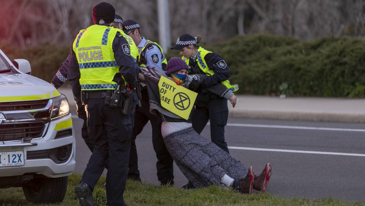 An Extinction Rebellion protester is arrested on Kings Avenue Bridge after causing major traffic jams. Picture: Keegan Carroll.