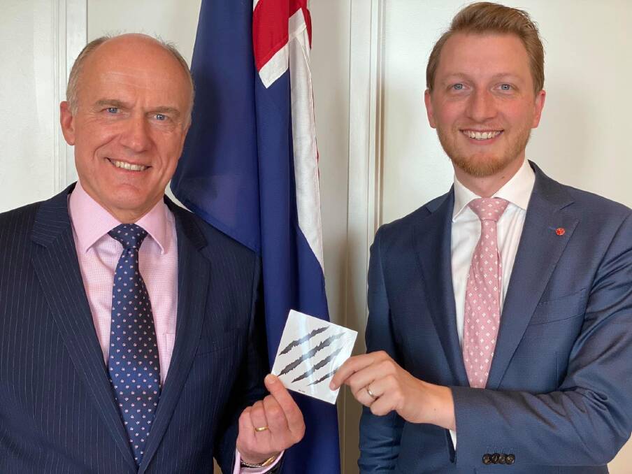 Liberal senator James Paterson presents his colleague Senator Eric Abetz with a sticker to mark his membership of the Wolverines. Picture: Supplied