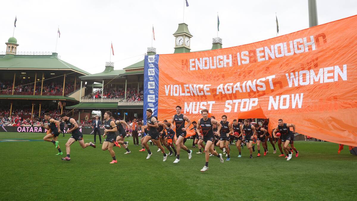 The GWS Giants run through a banner calling out domestic violence. Picture Getty Images