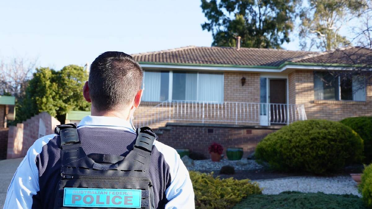 An ACT police officer outside the Fisher house on Monday. Picture ACT Policing