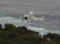 The Toll rescue helicopter hovers off Port Kembla on Monday, during the search for a missing 19-year-old swept off rocks. Picture: Robert Peet