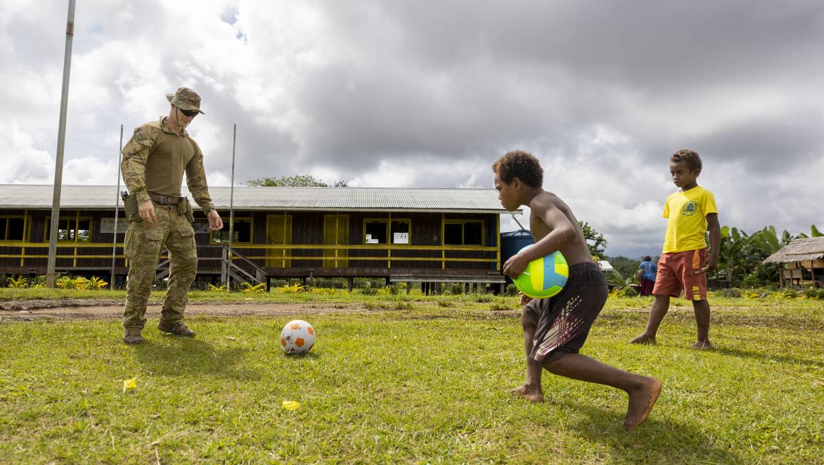 The children join Lance Corporal Hayden Pownall for a game of soccer. Picture Defence
