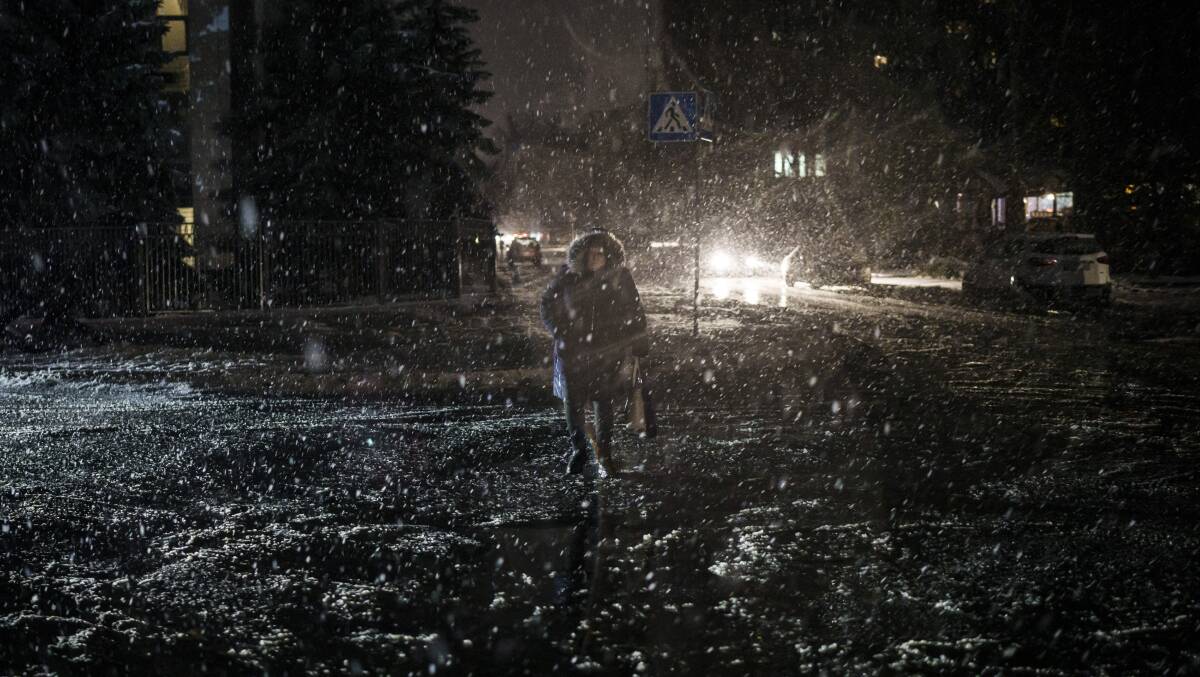 A woman crosses the street during snowfall as power outages continue in Kyiv. Picture AP