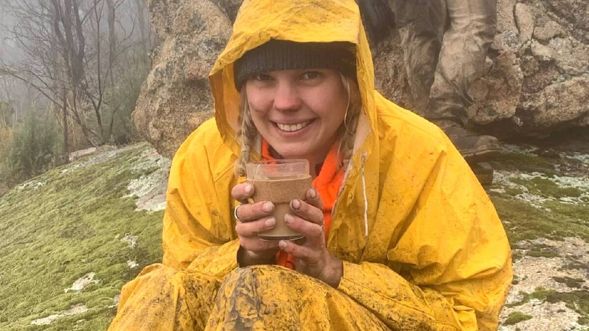 Labourer Zoe Cuthbert warms up with a hot drink on a cold wet day during the construction of the new Mt Tennent track. Picture: Iconic Trails