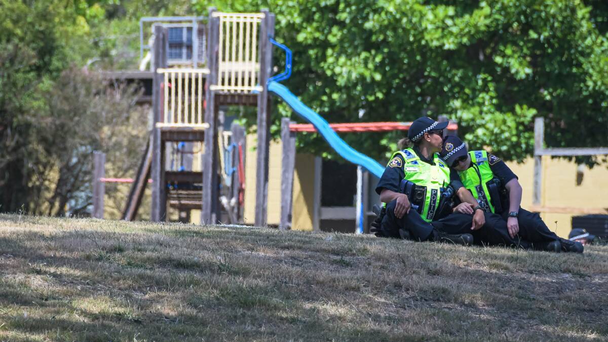 Heartbroken: Two police officers console each other in the grounds at Hillcrest Primary. Picture: Simon Sturzaker. 