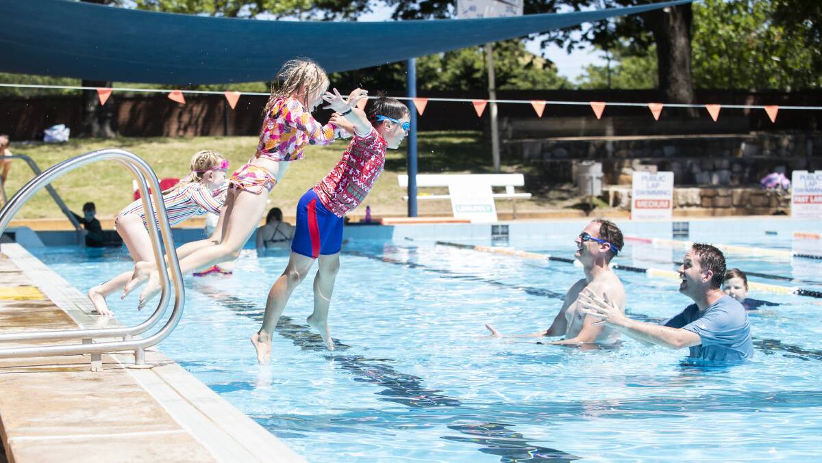 Steve and Johnathan, 8; Lenthall enjoy the water at Dickson pool with friends Mick; Emma, 8; and Katie, 6; Fox from Amaroo. Picture: Keegan Carroll
