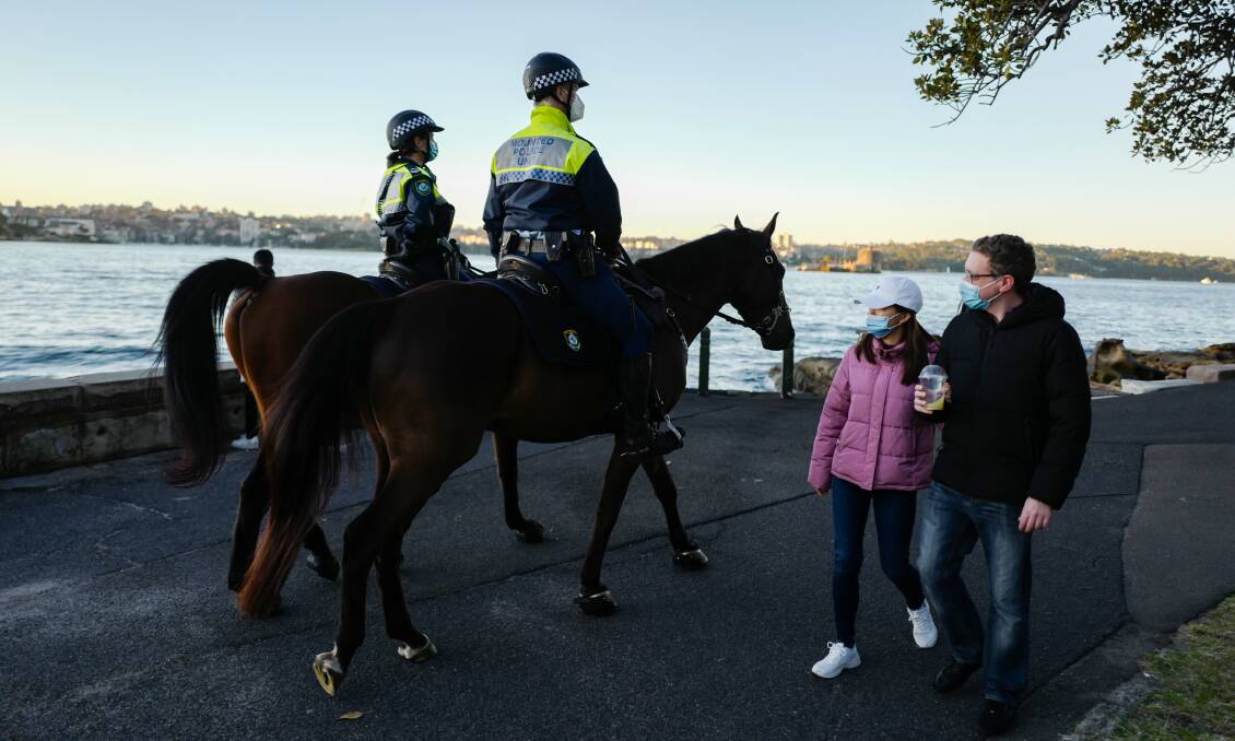 Two mounted police officers pass a man and a woman wearing face masks at Mrs Macquarie's Chair in Sydney. Picture: James D. Morgan/Getty Images