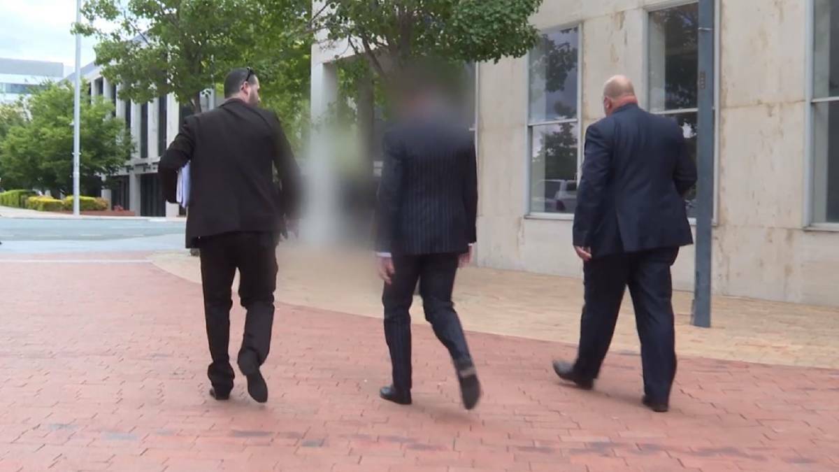 A Canberra lawyer (centre) arrested after a raid at a Civic law firm walking with two police towards the City Police Station on Wednesday. Picture: ACT Policing
