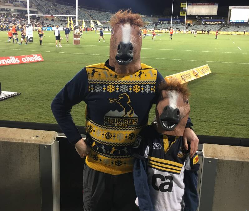 Father and son footy fans ready to cheer on the mighty ACT Brumbies on a cold Saturday night. 