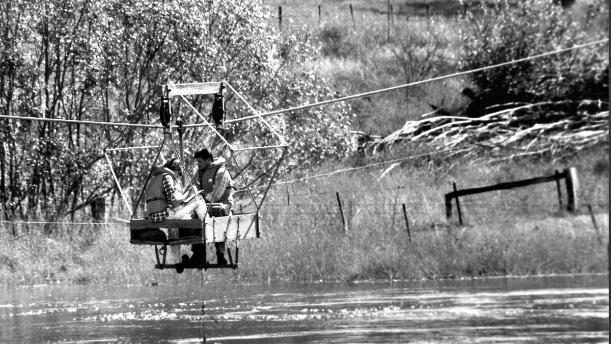 ACTEW staff check floodwater flow rates from a flying fox over the Molonglo River at Oaks Estate in 1989. Picture: ACT Heritage Library