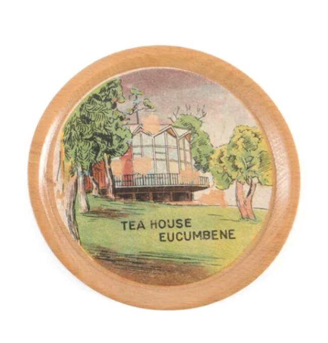 A wooden coaster featuring the Eucumbene Tea House, part of a set of six coasters produced by the Snowy Mountains Authority in 1958. Other scenes featured in the set include Cabramurra, Cooma, and Mt Kosciuszko Summit. Picture supplied