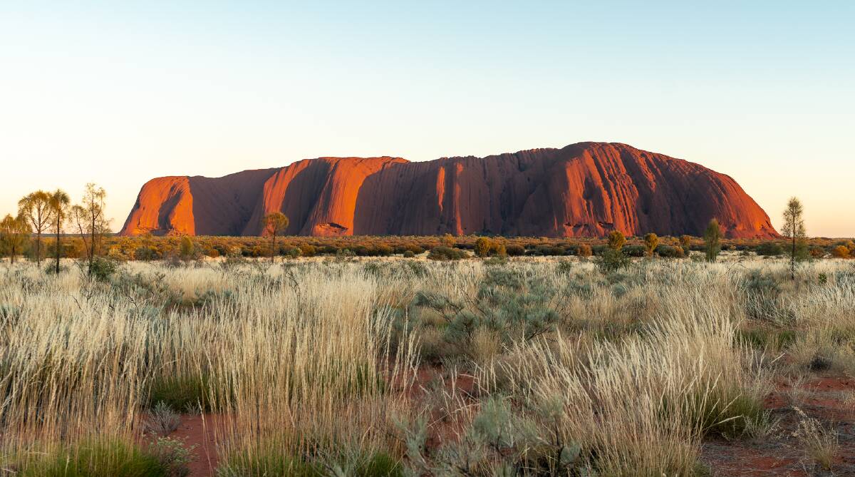 The first rays of morning light hit Uluru. Pictures: Michael Turtle