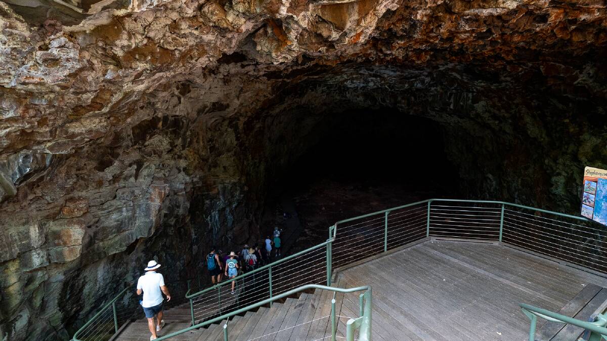 A tour heads down into a cave formed by a lava flow at the Undara Lava Tubes.
