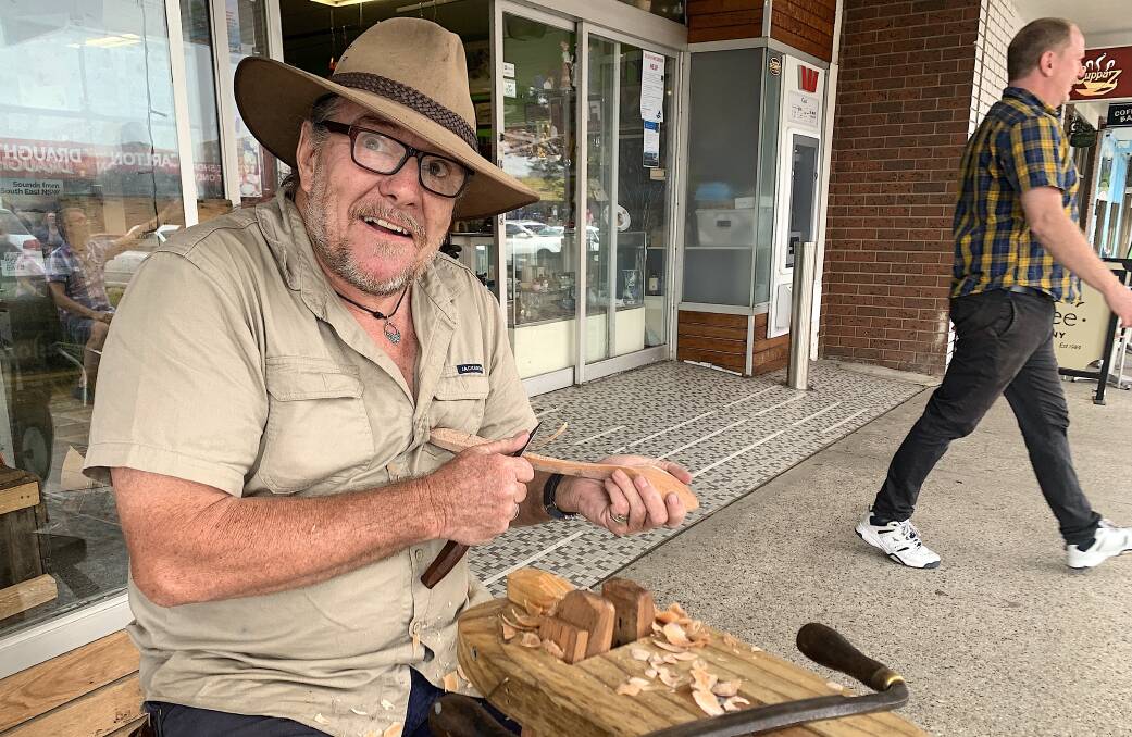 Paul Boyer carves a wooden spoon on the main street of Eden. Picture: Tim the Yowie Man