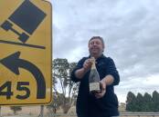 Gary Poile with one of hundreds of bottles of bubbly salvaged by local farmers after a 1983 crash on the Cullarin Range between Breadalbane and Gunning. Picture: Tim the Yowie Man