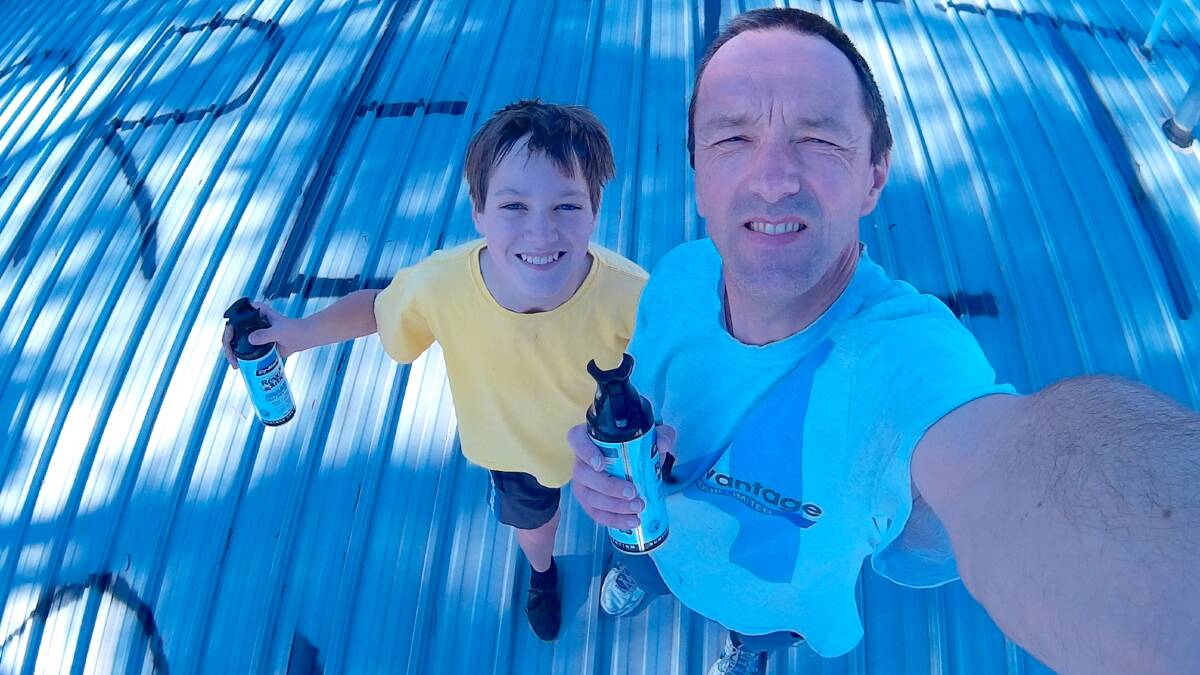Clayton Gumbrell and his son Samuel paint the unusual missive on their roof in November 2015. Picture: Clayton Gumbrell