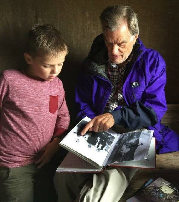 Klaus Hueneke reading from the Four Mile Hut logbook with grandson Ben in 2016. Picture: Abigail Curtis