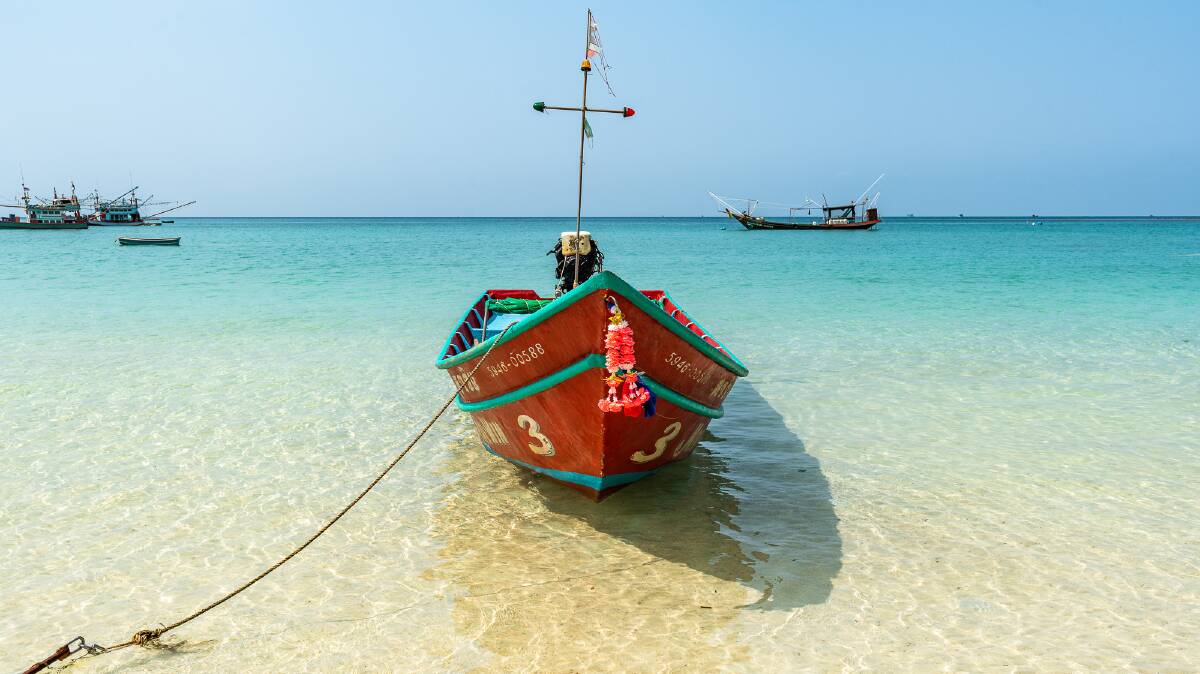 A traditional wooden boat tied up at a quiet beach on the island's north coast.