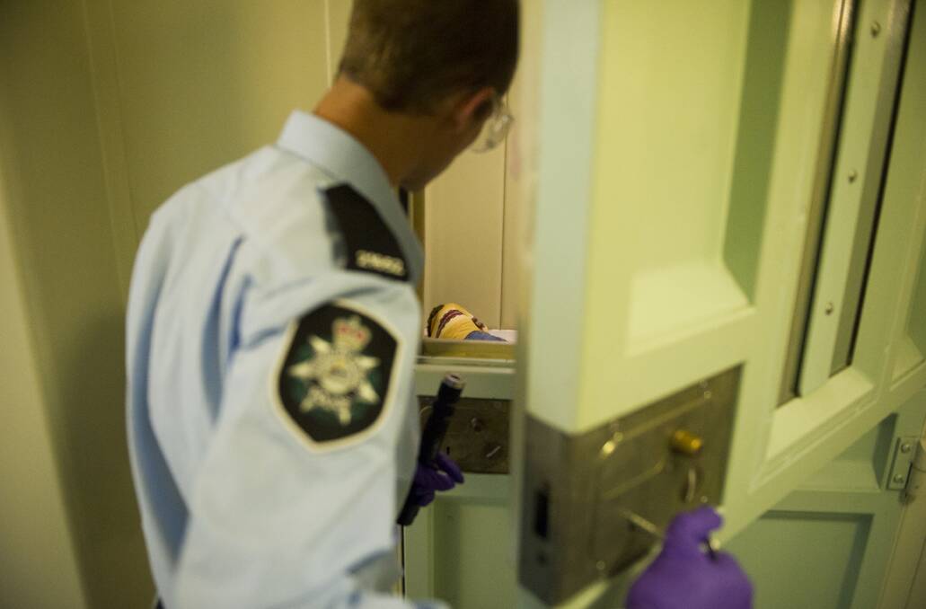 A police officer checks on a prisoner's welfare inside the ACT Watch House. Picture by Jay Cronan