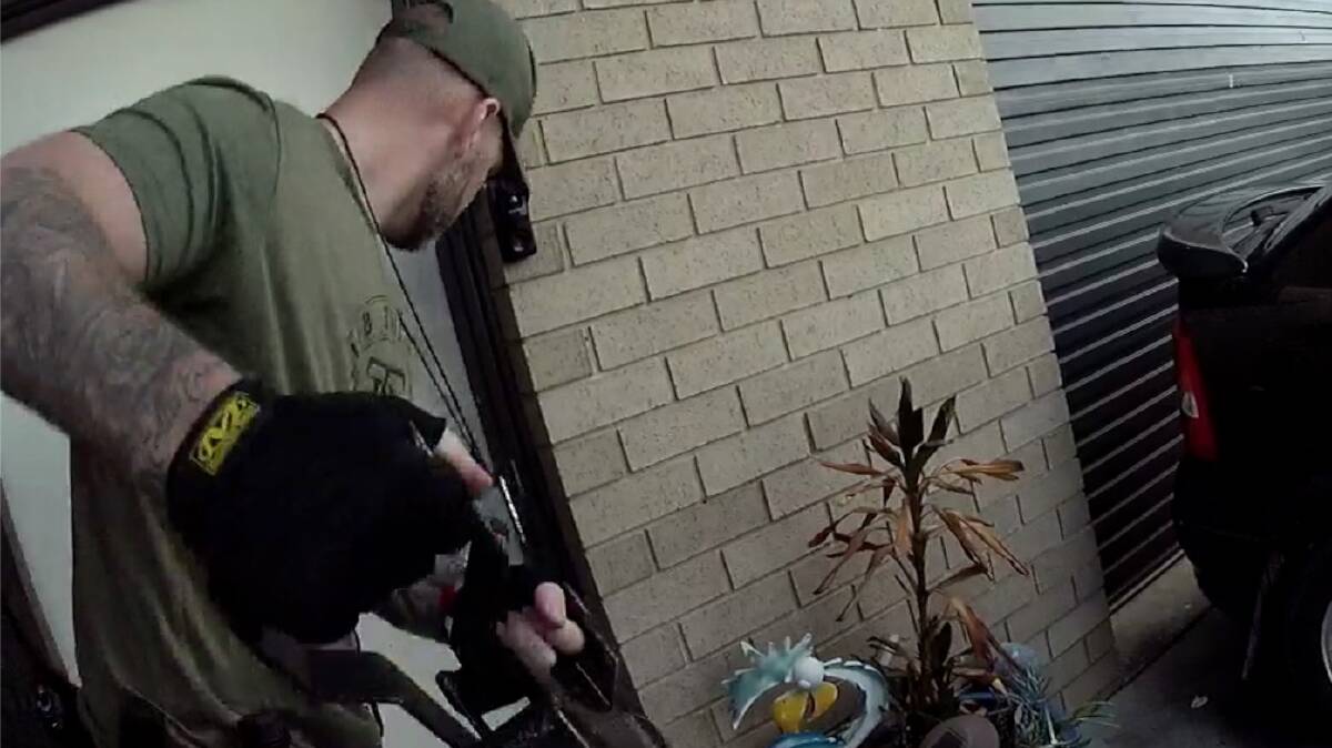 An Operation Toric officer prepares to force entry into a house during a raid on a known offender. Picture ACT Policing