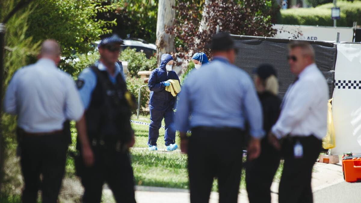 Homicide detectives wait for the crime scene to be cleared, while in the background forensics officers in full protective equipment begin the painstaking task of collecting evidence. Picture: Dion Georgopoulos 