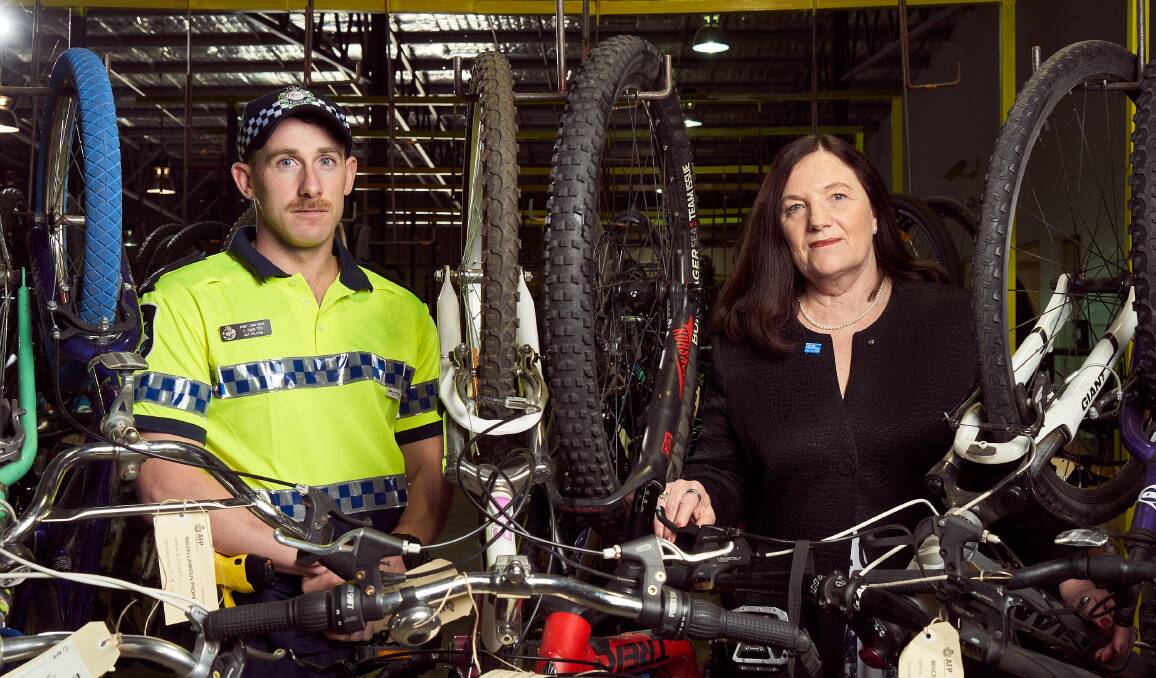 First Class Constable Chris Manton with Di Forrester, from Crime Stoppers ACT, among the dozens of unclaimed bikes held by police. Picture: Matt Loxton