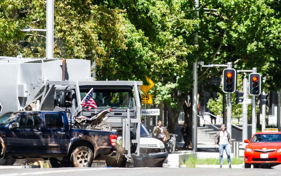 A garbage truck smashes into two parked cars, one of them a pick-up truck with a US flag, as part of the stunt sequence in Akuna Street. Picture: Karleen Minney
