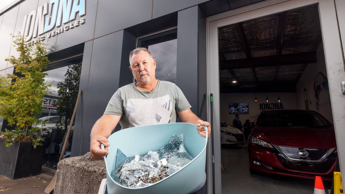 Rob Ogilvie carries out the broken glass from his showroom's front door after yet another Fyshwick burglary. Picture: Sitthixay Ditthavong
