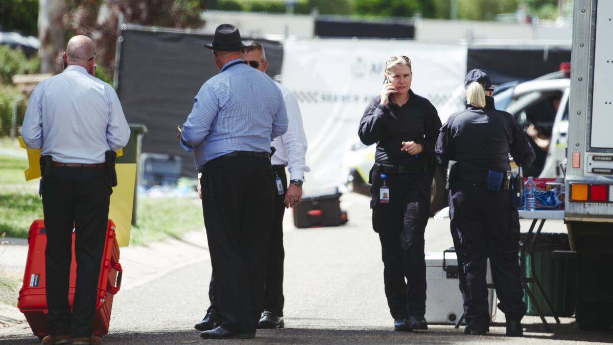 ACT Policing senior homicide team detectives, left, confer in Braine St, as forensic crime scene investigators, right, begin the process of collecting evidence. Picture: Dion Georgopoulos