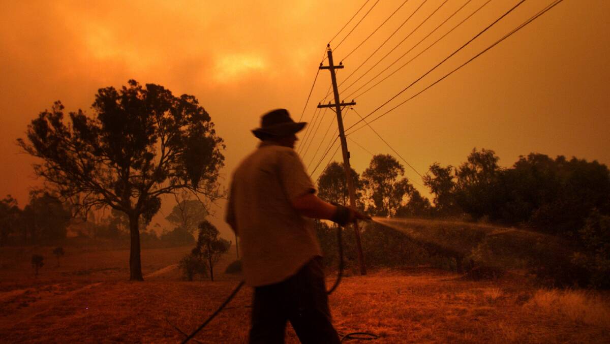 A Chapman resident protecting his property during the 2003 Canberra bushfires. Picture: Jacky Ghossein