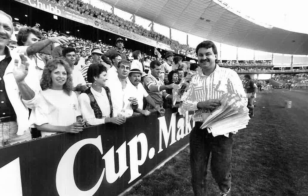 Canberra Times journalist Brad Turner hands out "We Did It" posters after the Raiders win the 1989 grand final. Picture: Graham Tidy