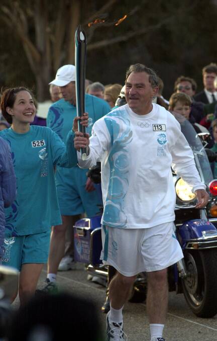 Former auxiliary Bishop of the Canberra-Goulburn diocese Pat Power running the flame towards Parliament House with escort runner Alicia Paul. Picture: Graham Tidy
