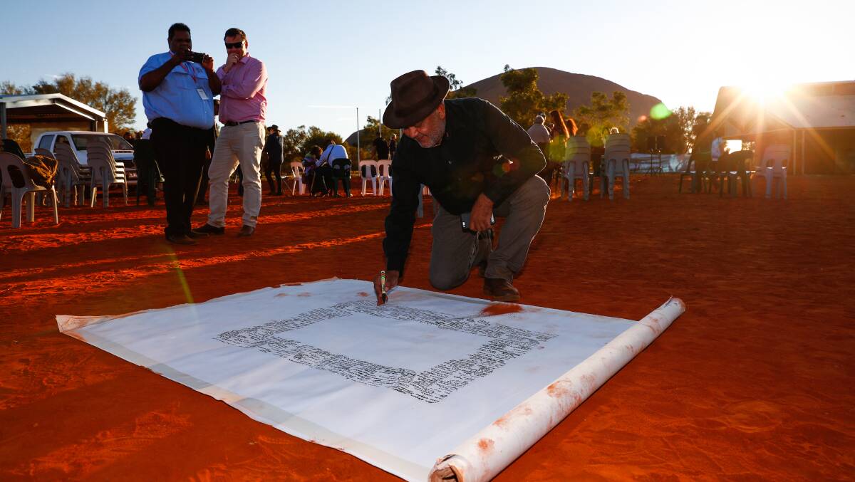 Noel Pearson signs the canvas where the Uluru Statement from the Heart will be painted on. Picture: Alex Ellinghausen