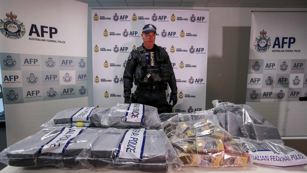 An AFP officer stands behind a significant quantity of seized cocaine and cash. Picture: Wayne Taylor