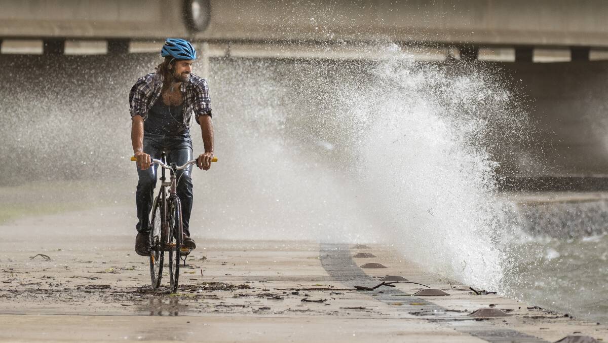 Robert Agostino, riding his bike as strong winds whip up waves along the lake front in Parkes. Picture Sitthixay Ditthavong