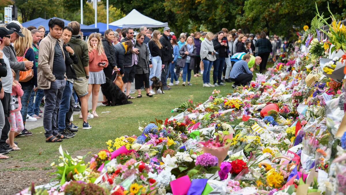 Aftermath: members of the public at a makeshift memorial in the Botanical Gardens in Christchurch. Picture: AAP
